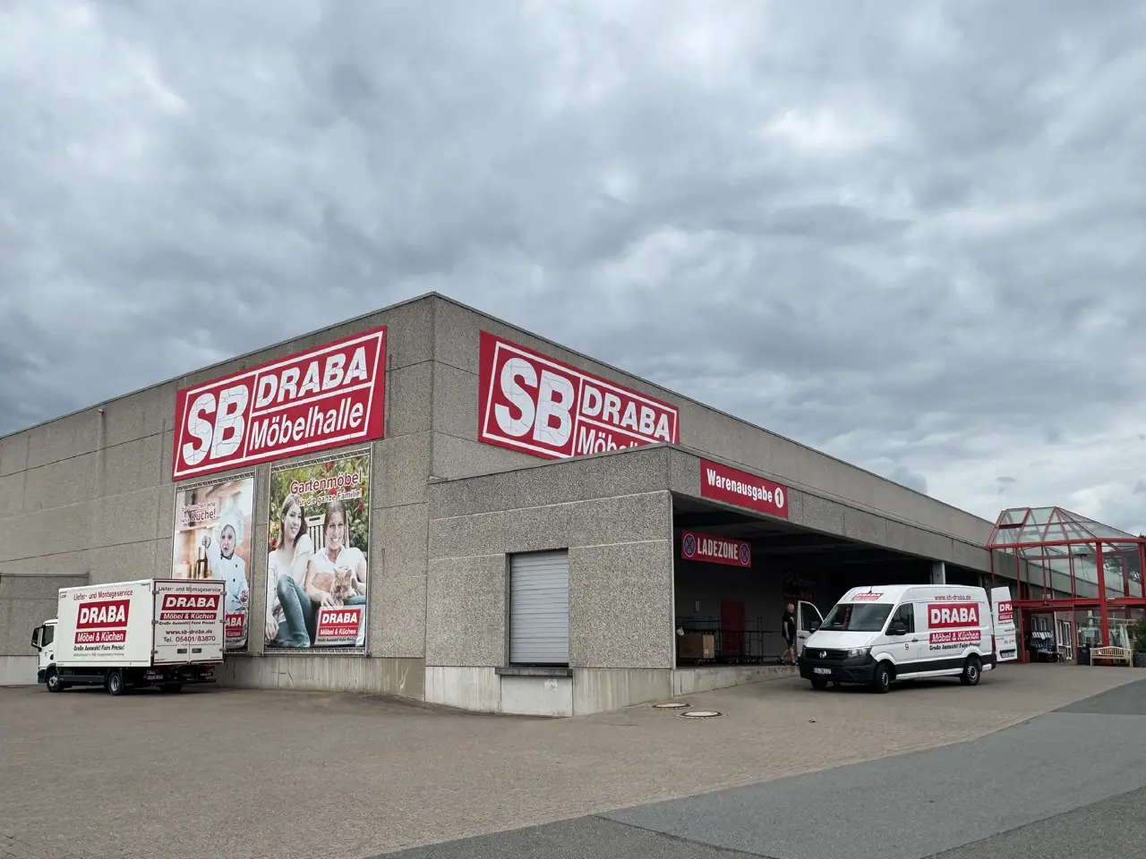 SB DRABA Möbelhalle mit Werbeschildern, Lieferfahrzeugen, Warenausgabe und Ladezone